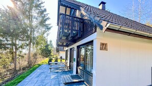 Ein modernes Gebäude mit Balkon, einer Terrasse mit Tisch und Stühlen und der Nummer 71 an der Wand.