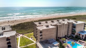 Un hotel con piscina en la azotea, vista al mar y zona de estacionamiento.
