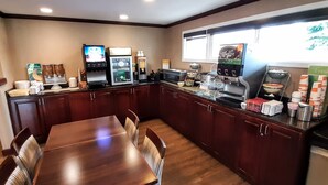 Een moderne keuken met een houten tafel en stoelen, uitgerust met een koffieapparaat, magnetron en diverse keukenapparaten.