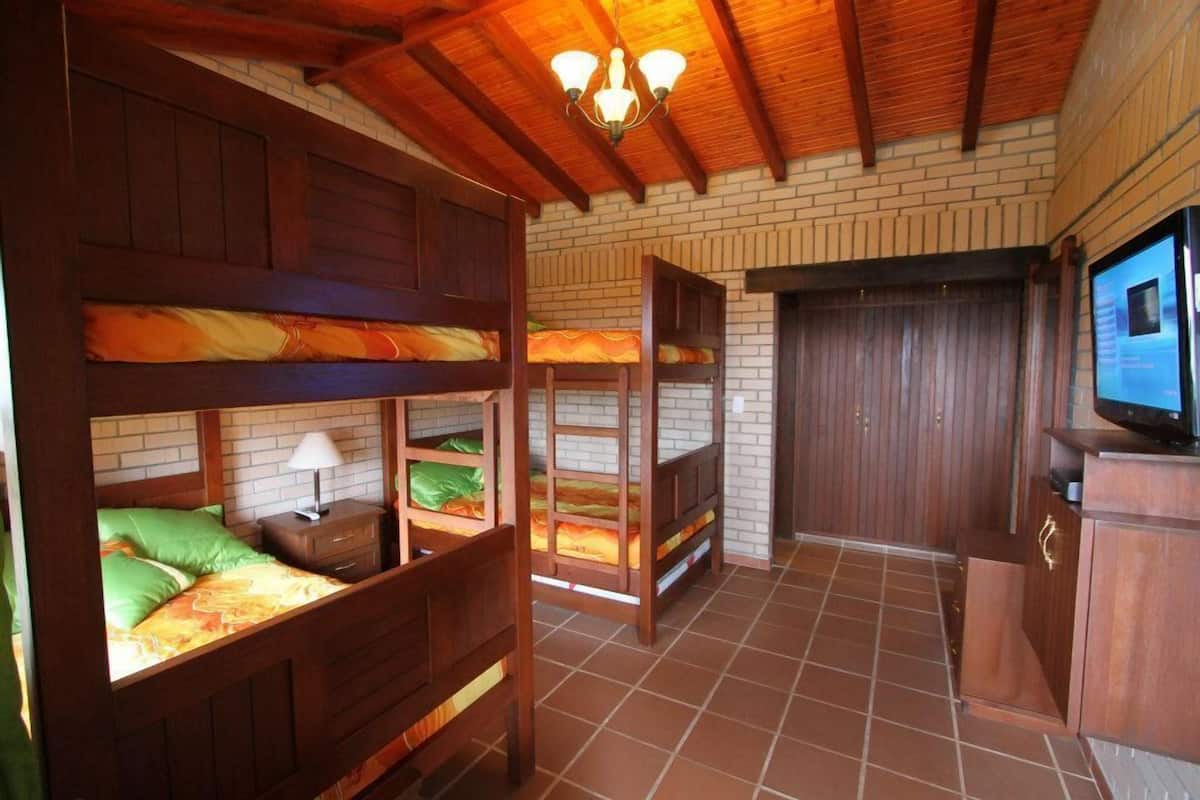 A room with bunk beds, a television, and a brick wall.