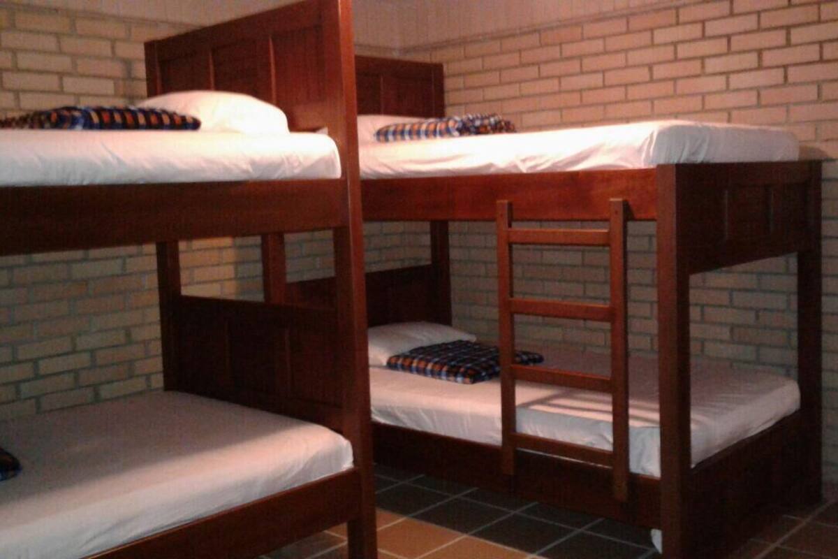 Bunk beds with wooden frames and white bedding, set against a brick wall.