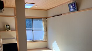 A room with tatami flooring, a low table, a television on a stand, and a window with curtains. - Kawayu onsen Minshuku SUMIYA (Tanabe)