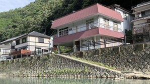 A two-story building with a red roof and white walls, located beside a clear water body. - Kawayu onsen Minshuku SUMIYA (Tanabe)