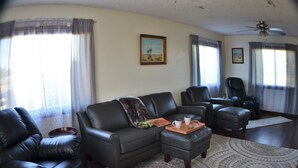 Ein Wohnzimmer mit einer Couch, zwei Sesseln, einem Couchtisch und einem Deckenventilator.