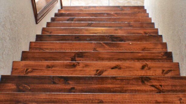 Eine Holztreppe führt zu einer Tür mit einer Glasscheibe.