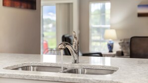 Una cocina con un lavamanos doble, encimera de mármol y vistas al exterior.
