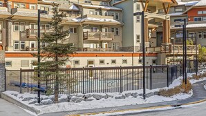 Un hotel de varios pisos con balcones, una zona exterior cubierta y un paisaje nevado.