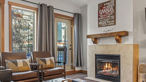 Una sala de estar con chimenea, sofás de cuero y vistas a un balcón.