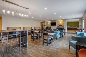 A modern hotel lobby with a bar area, seating arrangements, and a television screen. - MainStay Suites Bowling Green North (Bowling Green)