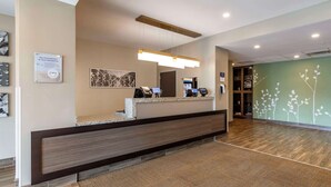Un espace d’accueil au design moderne, comprenant un comptoir d’accueil, un grand miroir et un panneau fixé au mur.