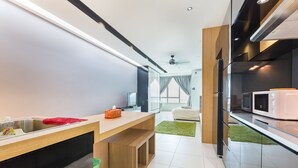 A modern kitchen with a wooden countertop, a sink, and a microwave. - Akademik Suites (Johor Bahru)