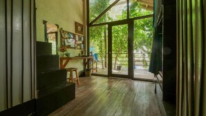Ein Zimmer mit Holzboden, einem Schreibtisch, einem Stuhl und einem großen Fenster mit Blick auf Bäume.