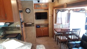 A compact RV kitchen with a sink, stove, and a small dining area with chairs and a table. - Near Blue Springs Pk (Orange City)