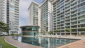 A modern high-rise residential building with a central courtyard featuring a swimming pool and decorative sculptures. - Palazio Serviced Apartment (Johor Bahru)