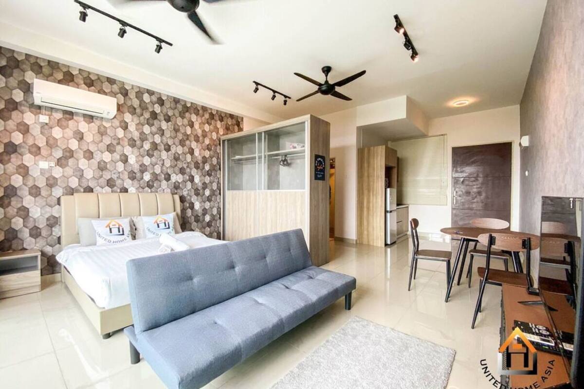 Een moderne hotelkamer met een bed, een bank, een eethoek en plafondventilatoren.