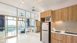 A modern kitchen with wooden cabinets, a built-in microwave, and a refrigerator. - Palazio Serviced Apartment (Johor Bahru)
