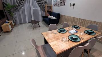 A dining area with a wooden table set for four, surrounded by chairs.