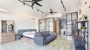 A modern bedroom with a grey sofa, a wooden dresser, and a large wardrobe. - Palazio Serviced Apartment (Johor Bahru)