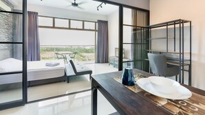 A modern hotel room with a balcony, a bed, a sofa, a dining table, and a chair. - Palazio Serviced Apartment (Johor Bahru)