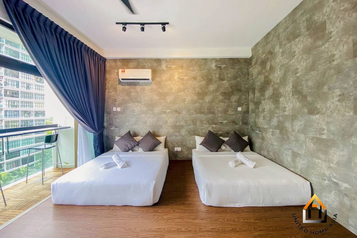 Een moderne hotelkamer met twee bedden, een plafondventilator, een airconditioner en een balkon met uitzicht op een stadsgezicht.