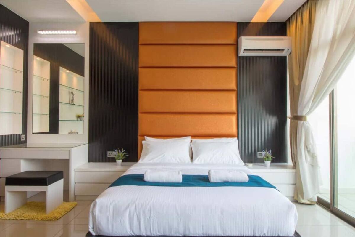 Een moderne hotelkamer met een groot bed, nachtkastje, spiegel en raam met gordijnen.