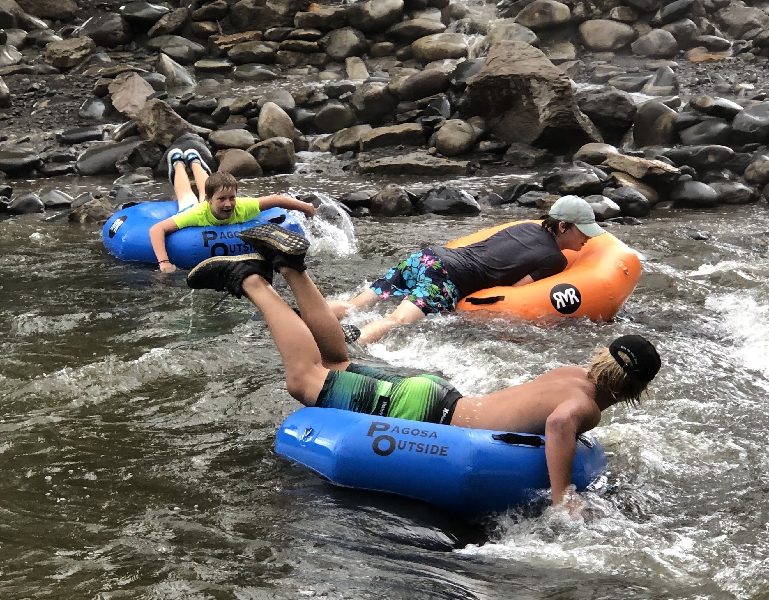 People on inflatable rafts in a river surrounded by rocks.