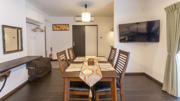 A dining area with a table set for six, surrounded by wooden chairs. An air conditioning unit is mounted on the wall above the table. - Hotel Houklea (Nago)