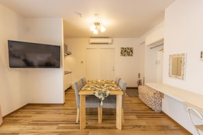 A dining area with a wooden table, grey upholstered chairs, and a floral table runner. - Hotel Houklea (Nago)