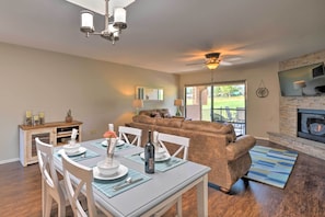 A dining area with a table set for four, a brown leather sofa, and a fireplace.