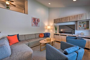 Ein modernes Wohnzimmer mit einer Eckcouch, einem Couchtisch und einem Fernseher.