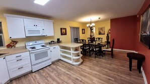 A modern kitchen with white appliances, a dining area with wooden chairs, and a red accent wall. - 6 Adults, Dogs OK see below . Breakfast , Olympic Nat. Park, Victoria ferry (Port Angeles)