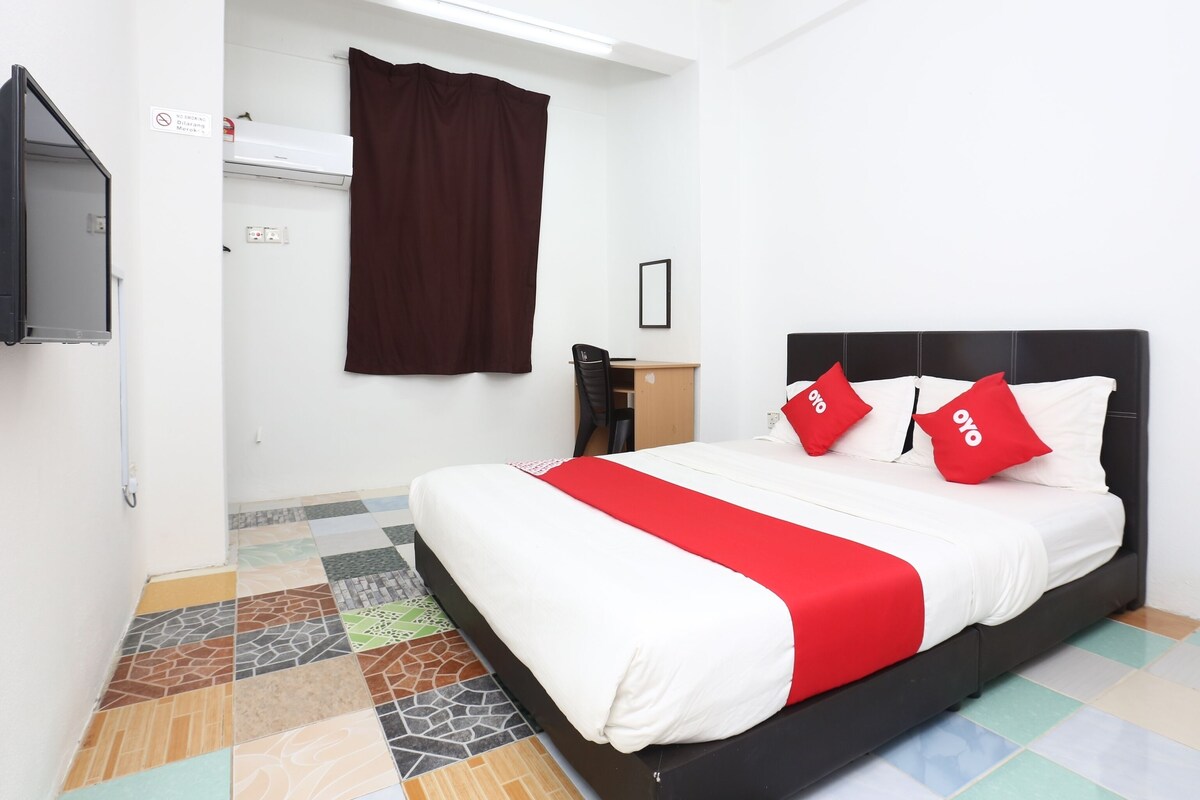 A hotel room with a bed, a desk, and a TV.