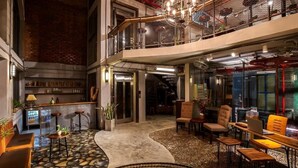 A spacious indoor area with a curved seating area, a bar, and a staircase leading to an upper level. - Bridges Danang Boutique Hotel (Da Nang)