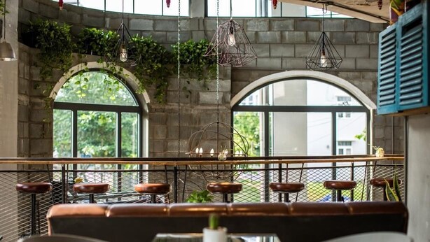 An interior with arched windows, hanging light fixtures, and a bar area with stools. - Bridges Danang Boutique Hotel (Da Nang)