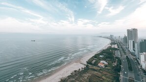 A coastal cityscape with a beach, high-rise buildings, and a clear sky. - Bridges Danang Boutique Hotel (Da Nang)