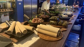 A kitchen area with a stainless steel refrigerator, a stove, and various cooking utensils. There are several bamboo tubes and a bowl of shredded meat on the counter. - Pi's Boutique Hotel (Sa Pa)