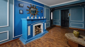 A room with blue walls, a fireplace with a white mantel, and a wooden floor. - Pi's Boutique Hotel (Sa Pa)