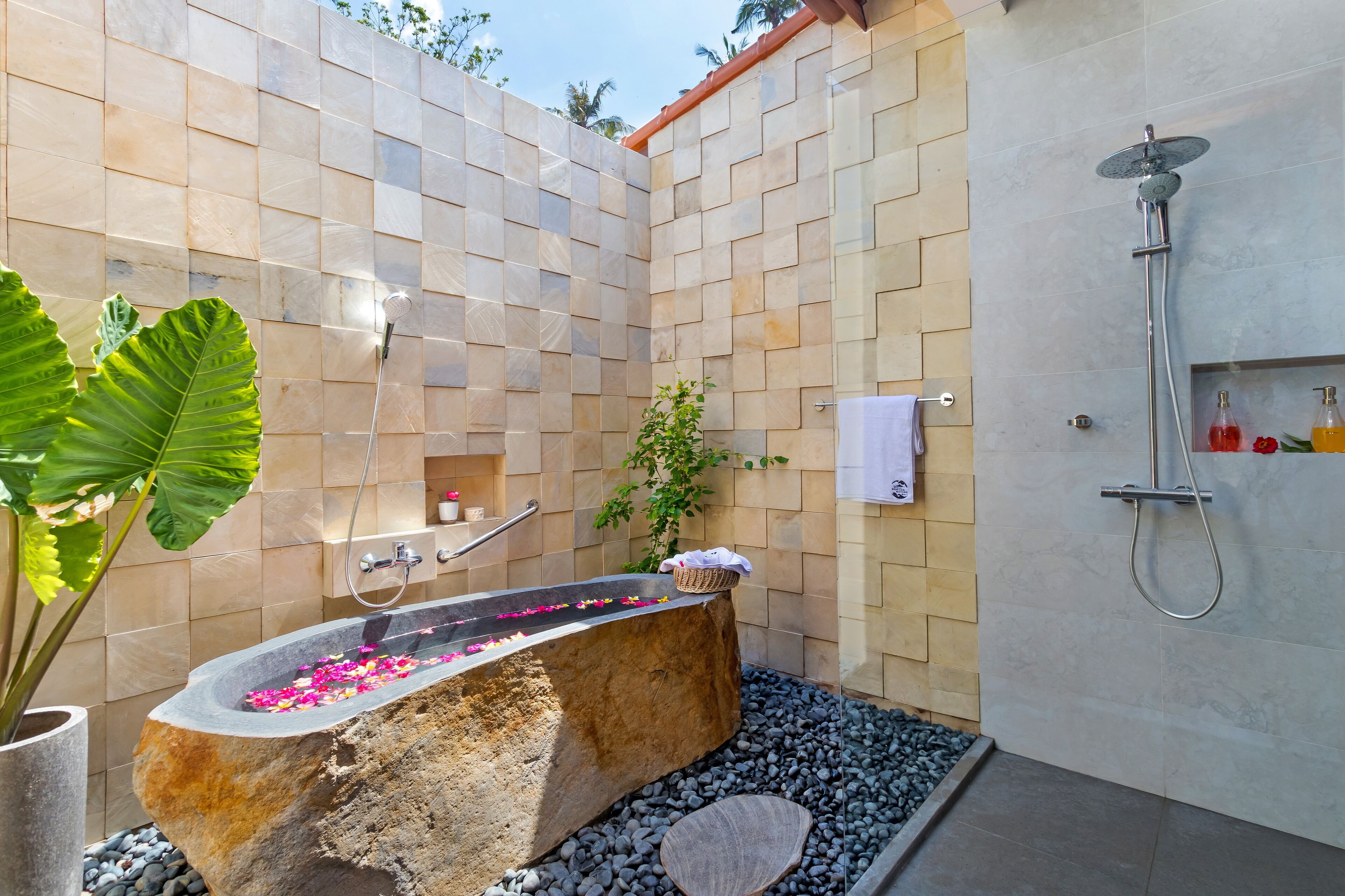 A modern bathroom with a stone bathtub, a shower, and a small shelf with toiletries.