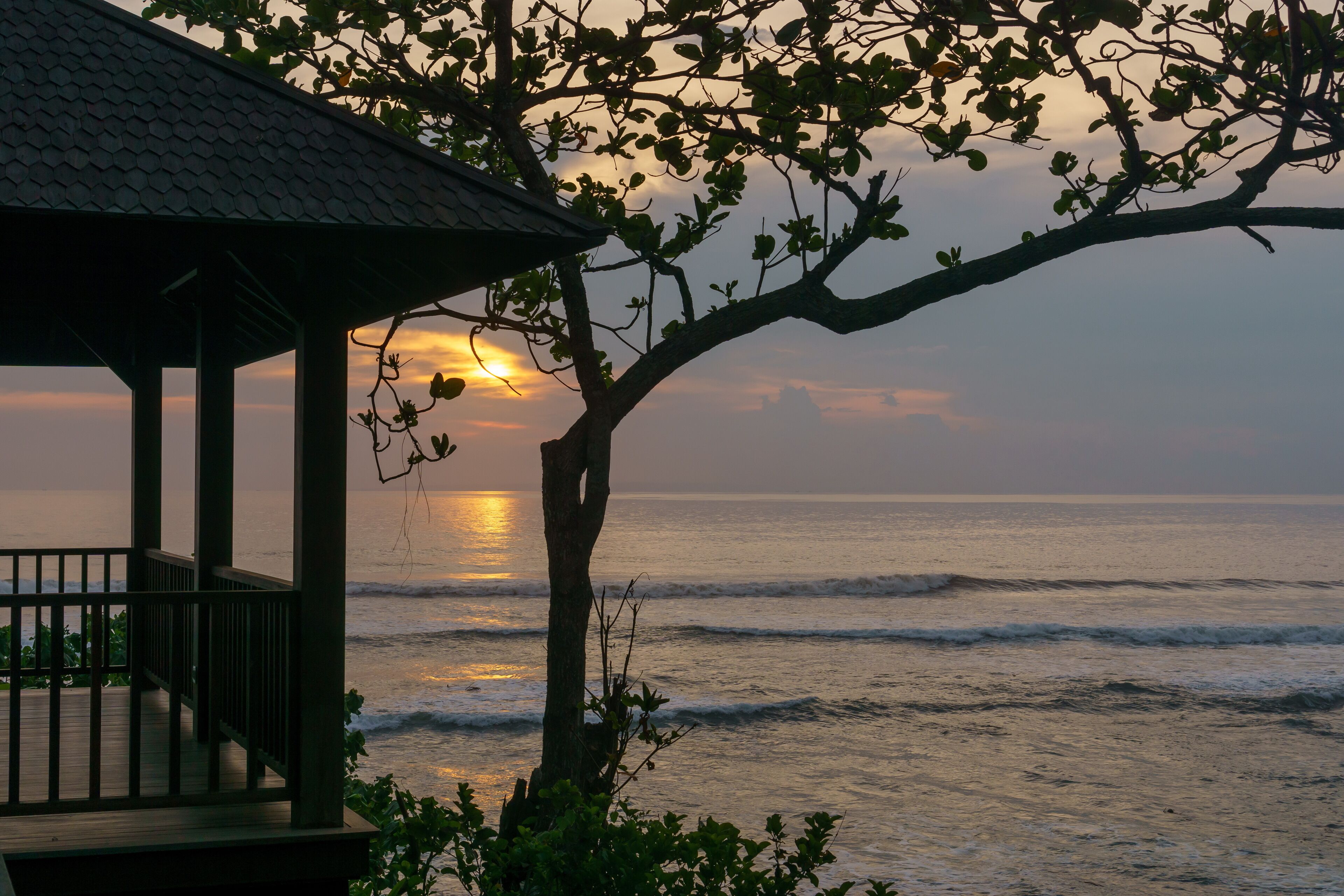Una pérgola con vista al océano al atardecer.