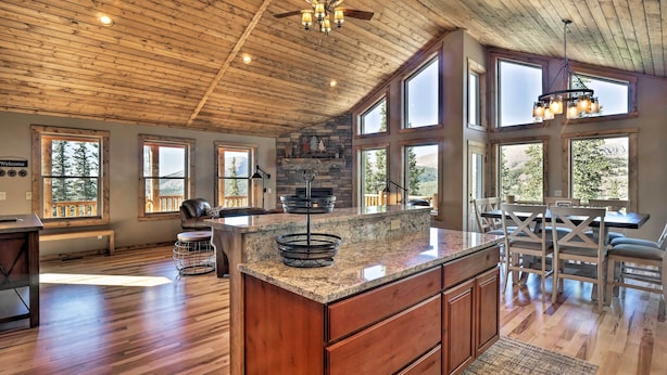 A spacious kitchen with a large island, wooden ceiling, and large windows offering views of the outdoors. - Fairplay Cabin w/ Wraparound Deck & Mountain Views (Fairplay)