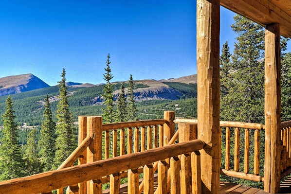 Une terrasse en bois dotée d’une rambarde, offrant une vue sur un paysage montagneux.