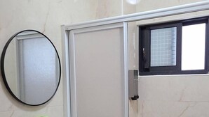 Un baño con lavamanos blanco, inodoro y ducha con cerramiento de vidrio.