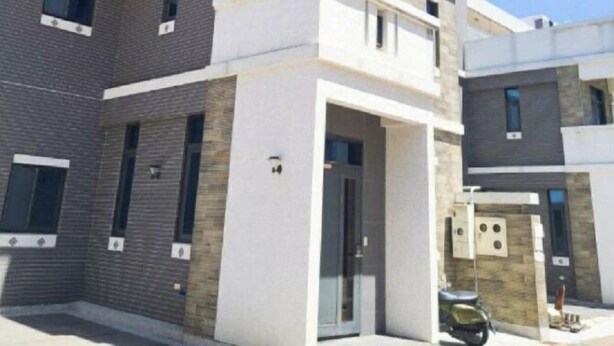 Un edificio residencial de varios pisos con balcones, un garaje y cielo despejado.