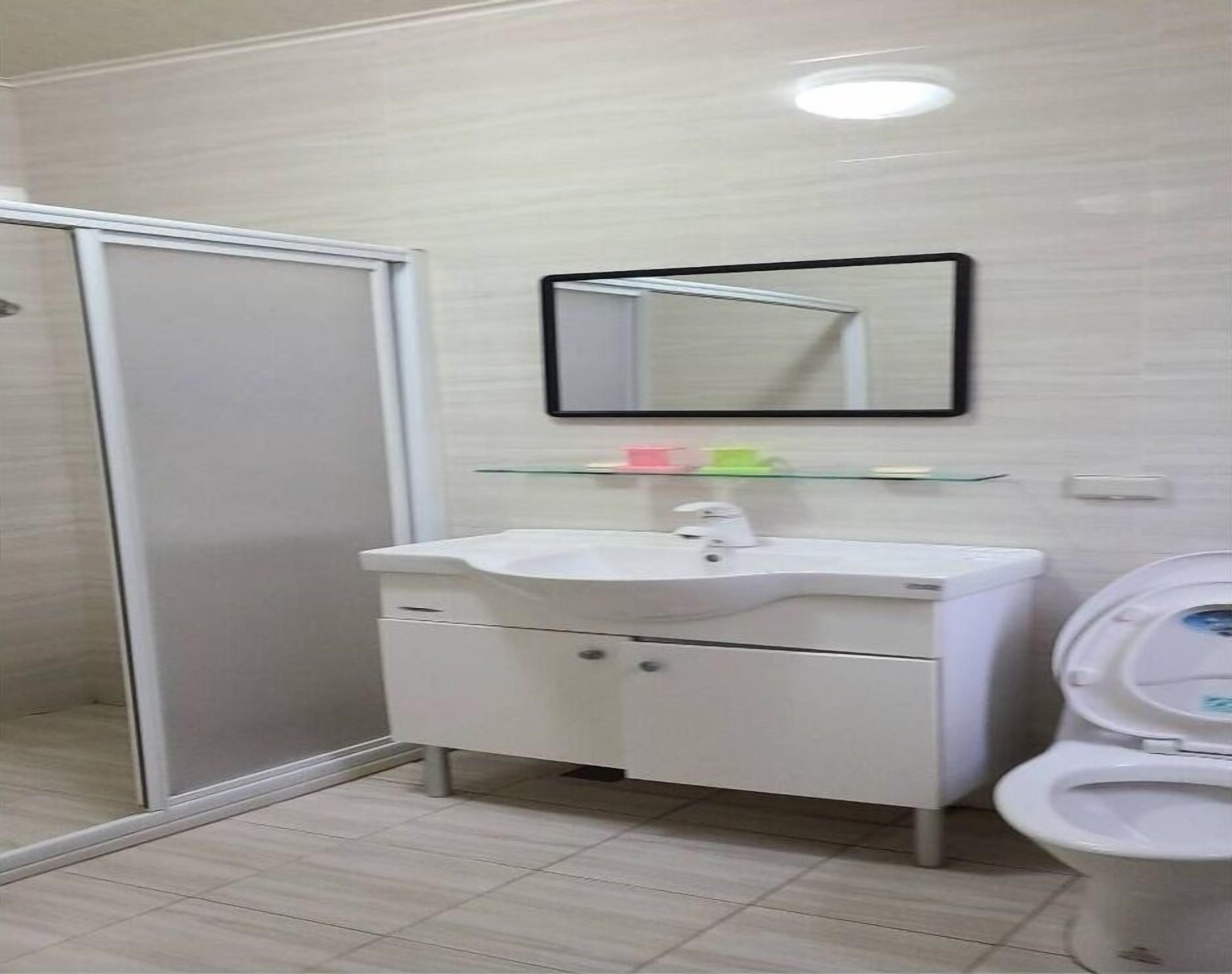 Un baño con un lavamanos blanco, un espejo y un inodoro.