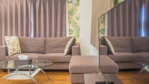Ein Wohnzimmer mit einer Couch, einem Glastisch und einem Spiegel.