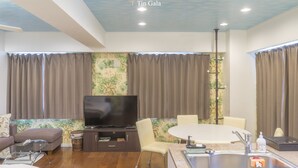 Ein modernes Wohnzimmer mit Flachbildfernseher, einem Esstisch und einer Küchenzeile mit Spüle.
