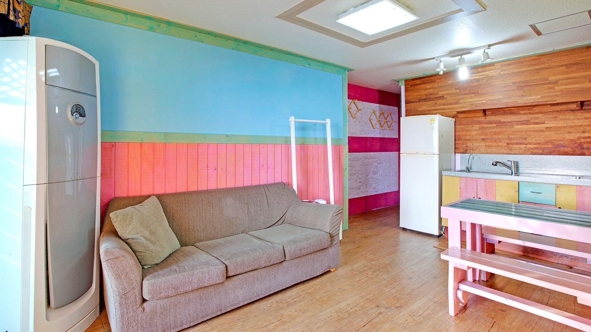 A compact living space with a sofa, kitchenette, and a colorful wall.