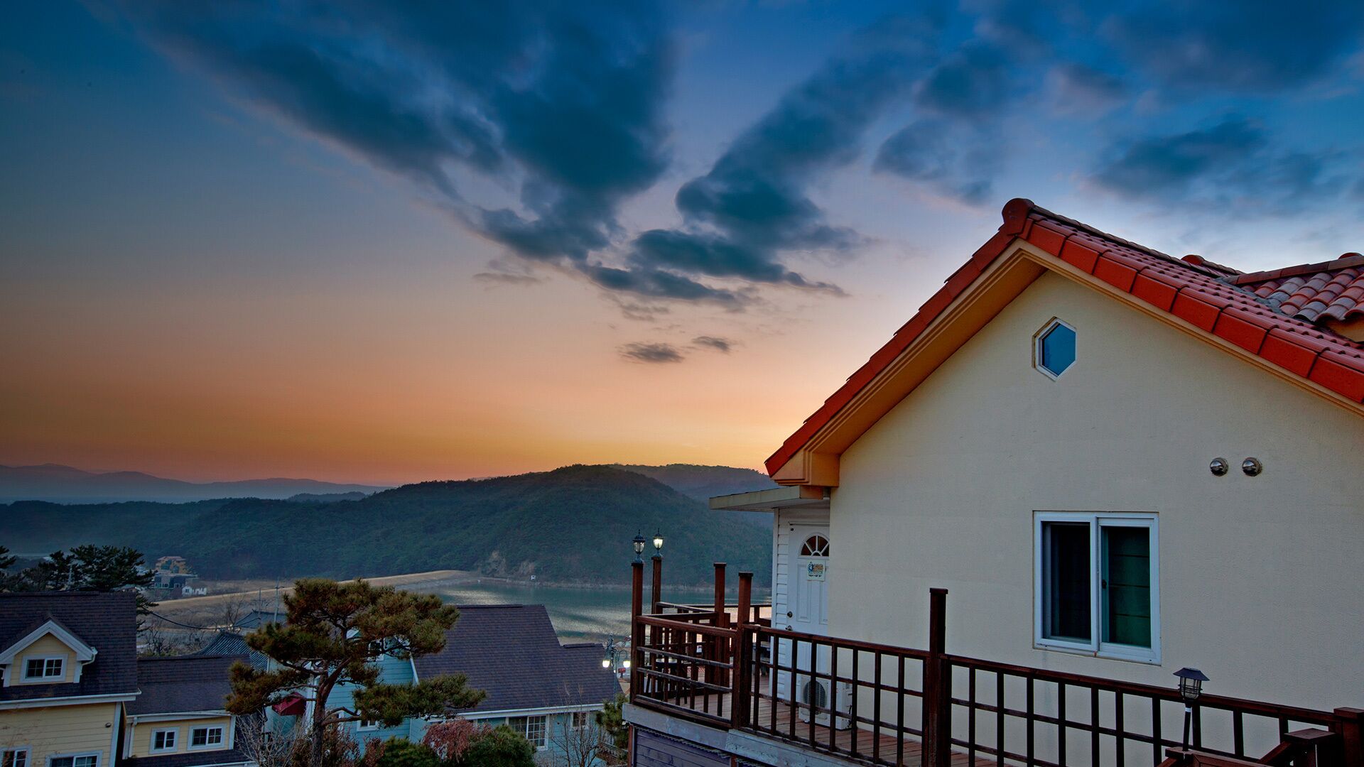 Ein Haus mit rotem Dach, einem Balkon und Blick auf einen See und Berge.