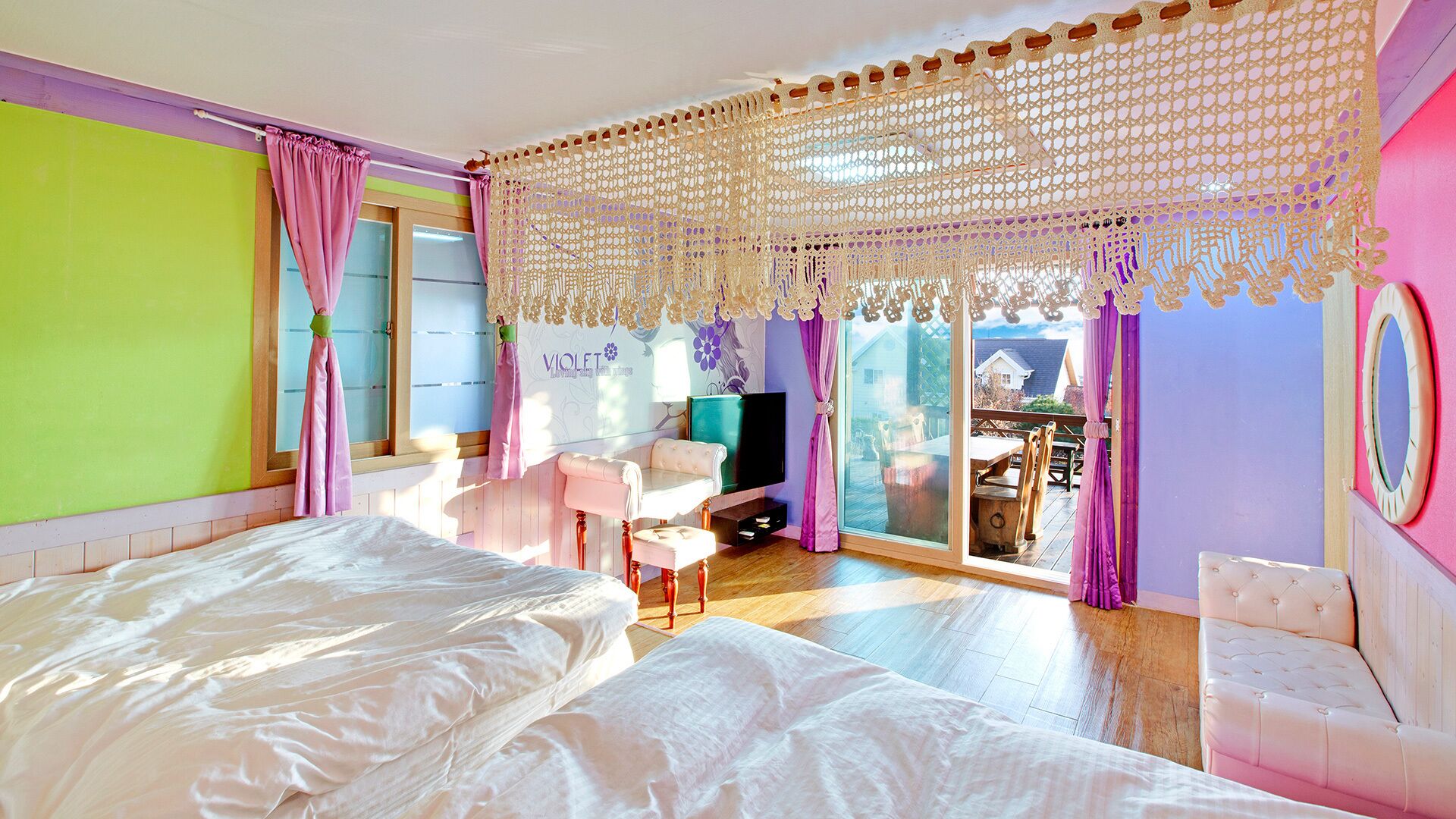 A bedroom with a large bed, a TV, and a balcony with a table and chairs.