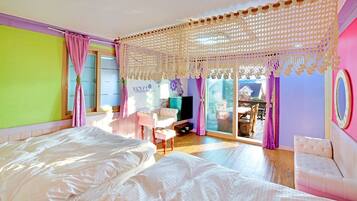 A bedroom with a large bed, a TV, and a balcony with a table and chairs.